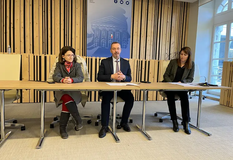 Trois personnes présentent un bilan à une table dans une salle de préfecture