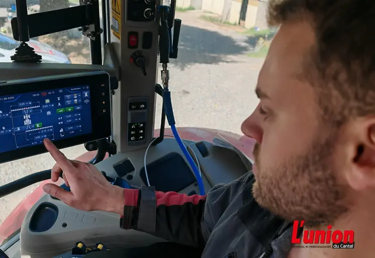 agriculteur dans la cabine de son tracteur pilote l'autoguidage sur un écran tactile.