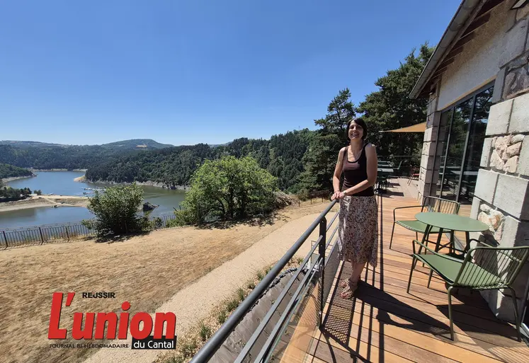 Une femme debout avec à sa droite le lac de Garabit. 