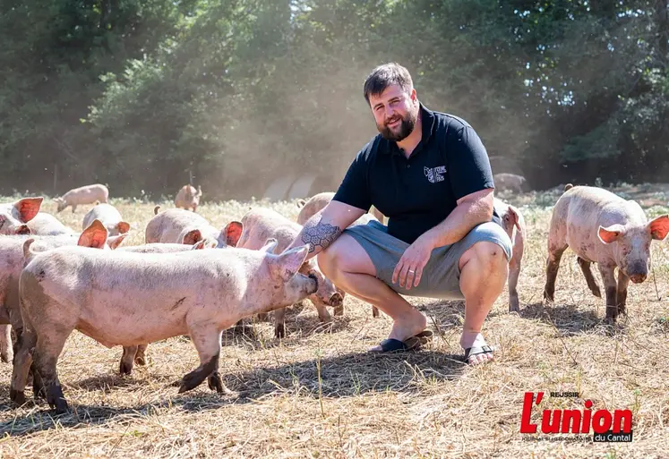 jeune éleveur de porcs plein air accroupi au milieu de ses animaux.