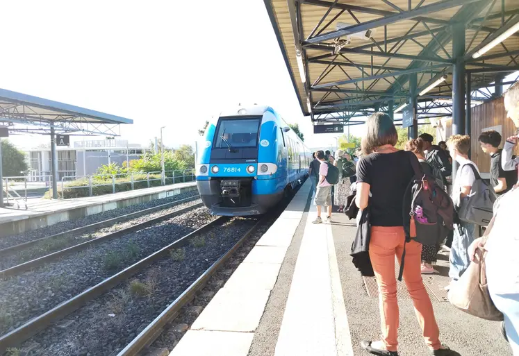 Quai de gare avec un train de la Région Auvergne Rhône-Alpes.