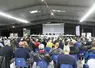 Le public, assis sur des chaises plastiques, écoute les explications à la tribune lors de l'assemblée générale des chasseurs de Lozère