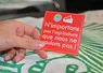 Une main tient un sticker avec écrit "n'importons pas l'agriculture que nous ne voulons pas"