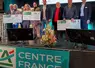 des gens sur un podium posent avec un chèque en main