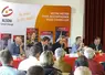 5 hommes assis derrière une table, face à une assemblée