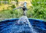robinet d'eau ouvert au dessus d'un baquet