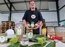 Un homme en tablier noir présente une gamme de produits transformés à base de châtaignes.