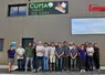 un groupe d'agriculteurs devant le pignon d'un bâtiment agricole avec le logo d'une Cuma