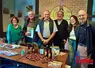 Un groupe de personnes débout, devant une table remplie de produits à la châtaigne. 