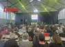des gens de dos dans une salle avec au fond un écran lumineux