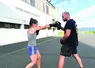 Une jeune femme et son entraîneur en train de faire semblant de se battre avec des gants de boxe.