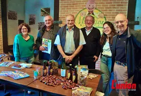 Un groupe de personnes débout, devant une table remplie de produits à la châtaigne. 