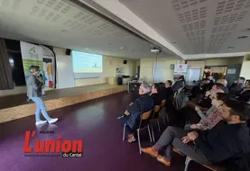 une sale avec une personne debout à gauche s'adressant à un groupe de personnes à droite de la photo