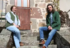 Une jeune femme et un jeune homme posant, assis sur les escaliers d'une vieille maison en pierre