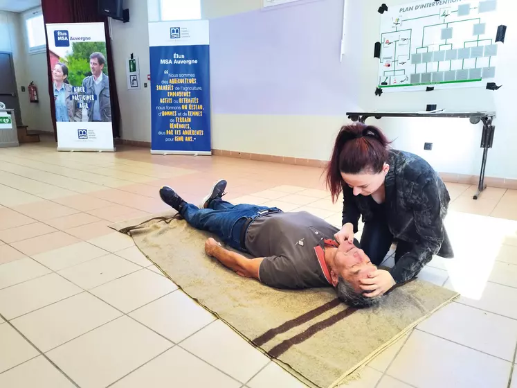 Une femme montre comment positionner la tête d'une personne inconsciente sur le sol, pour lui faire du bouche à bouche.