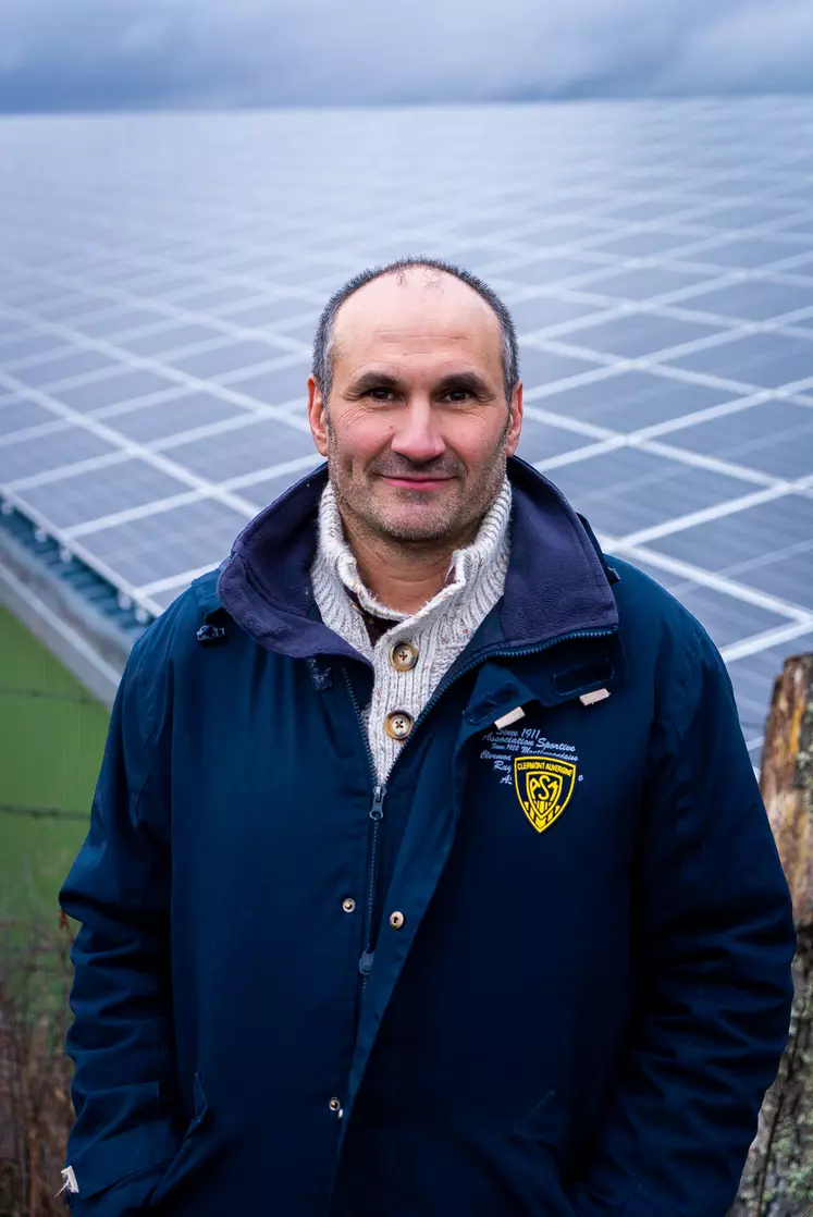 Un agriculteur devant un hangar dont la toiture est couverte de panneaux photovoltaïques.