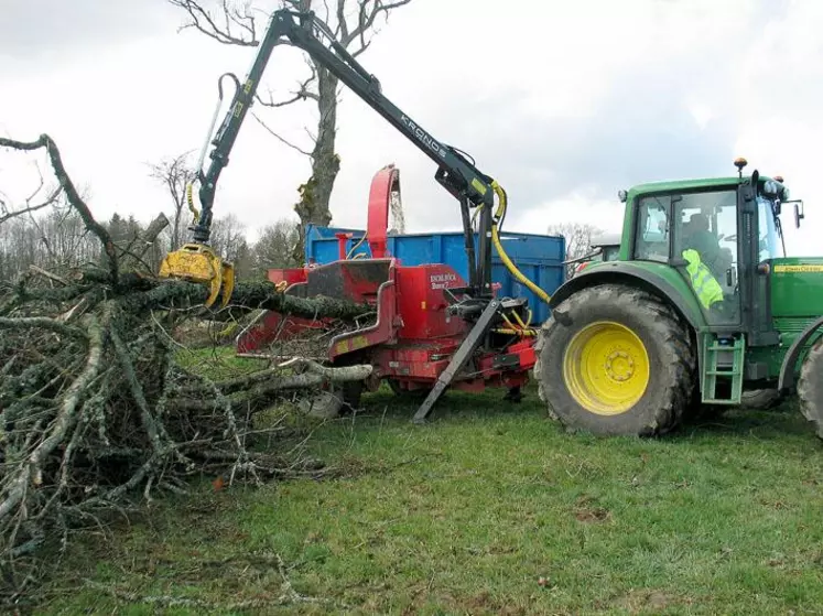 Le conducteur saisit les branches au moyen d’un grappin et les insère dans le rotor qui les déchiquète au moyen des deux rouleaux crénelés. Le produit est disposé dans la benne.