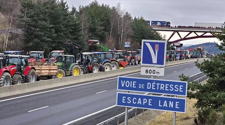 Tracteurs bloquant l'A75 en Lozère avec panneau "Escape lane, voie de détresse" au premier plan