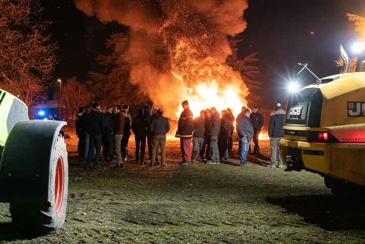 Un groupe de gens dehors devant un feu dans la nuit.