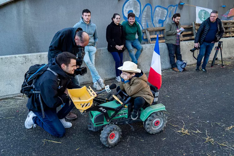 Un enfant sur un tracteur à pédales, interviewé par la télévision.