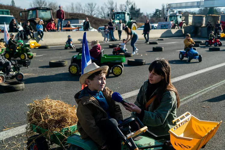 Un petit garçon sur un tracteur à pédales, interviewé par la radio.