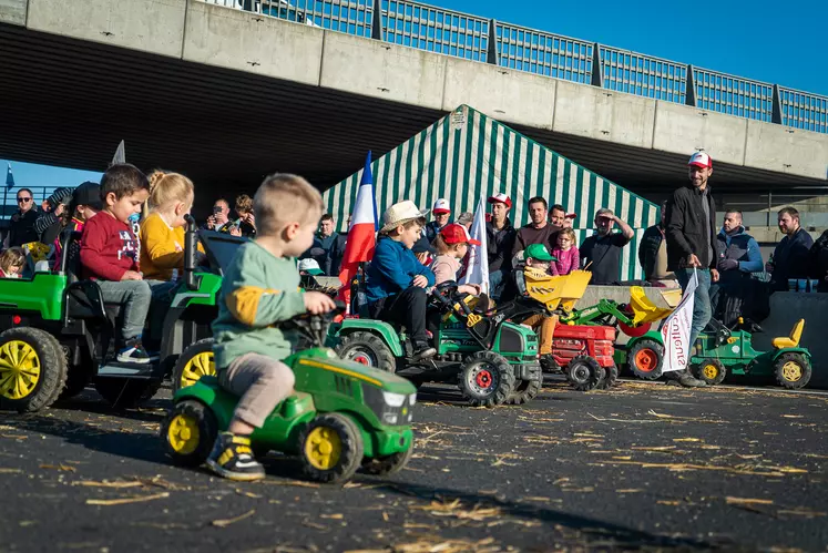 Groupe d'enfants en ligne sur leurs tracteurs à pédales.