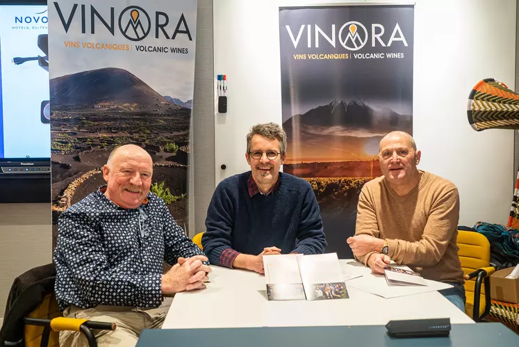 Trois hommes assis devant des kakémonos Vinora.