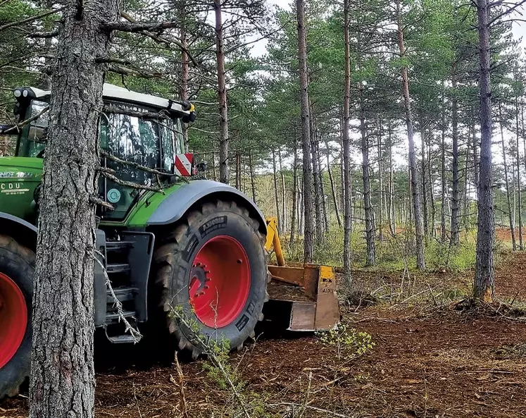 Un tracteur dans un sous-bois avec une remorque