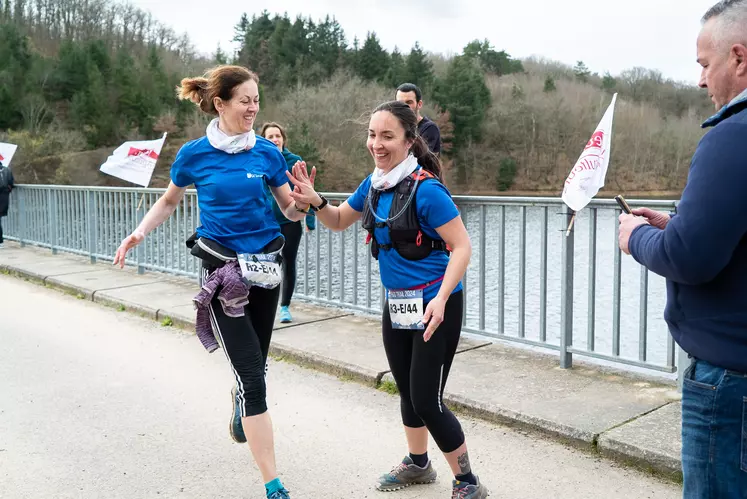 Deux coureuses se tapent dans la main sur un pont.