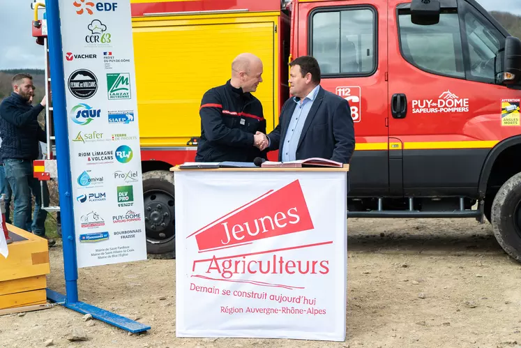 Deux hommes se serrent la main devant un camion de pompier.