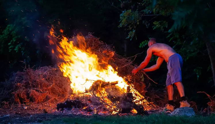 Homme faisant brûler des déchets verts.