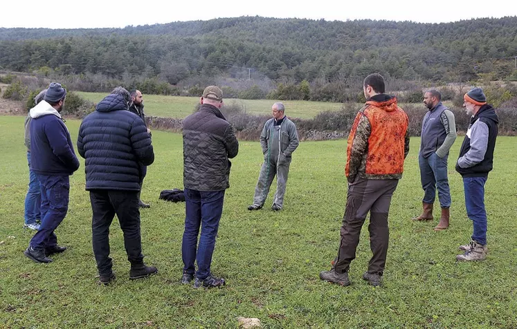 Un groupe d'hommes discute en rond au milieu d'une parcelle agricole.
