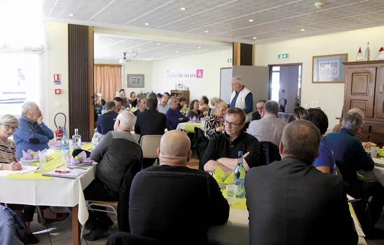 Une personne, debout, parle, un groupe assis à table l'écoute.