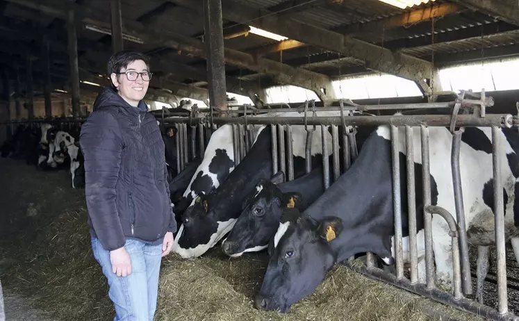 L'agricultrice Anne-Laure Fraisse sourit aux côtés de son troupeau de Prim'Holstein en train de manger.