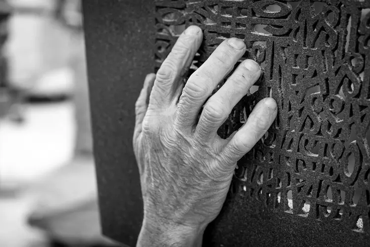 Une main posée sur une pierre sculptée