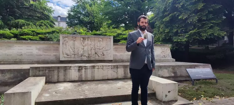 Un homme tenant une photo devant un monument aux morts