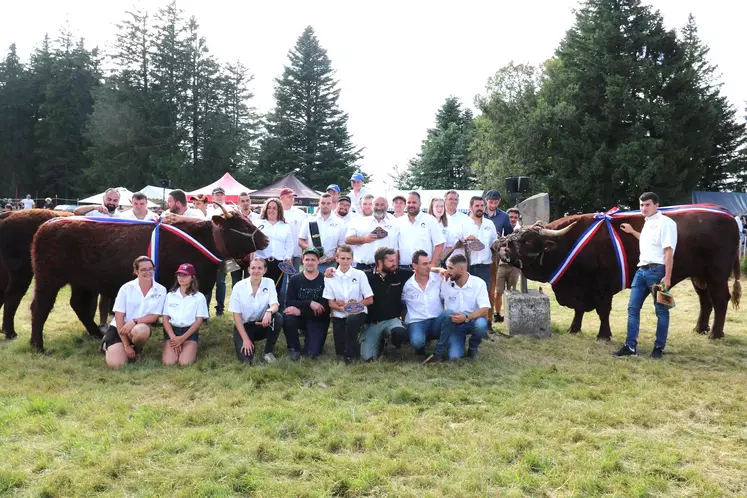 Un groupe de gens habillés en blanc posent à côté de vaches salers lors d'un concours