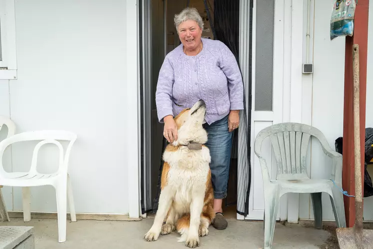 Une femme souriante caresse son chien sur le pas d'une porte