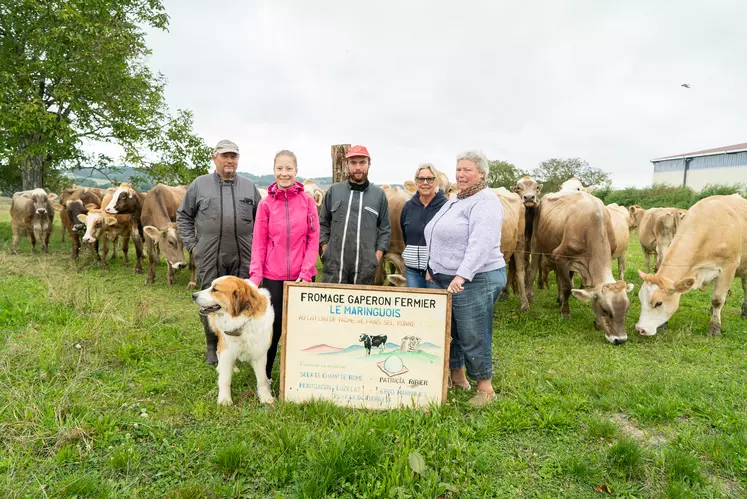 Une famille tenant un panneau devant un troupeau de vache dans la campagne