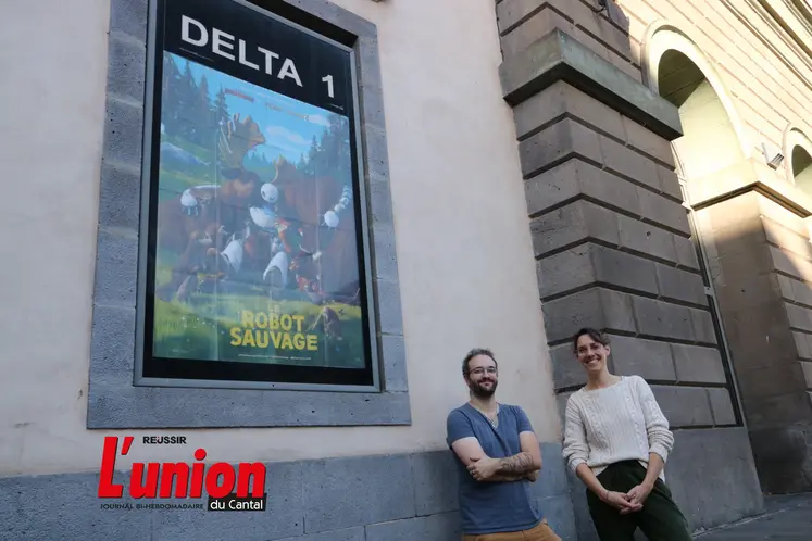 deux personnes devant un mur et une affiche de cinéma