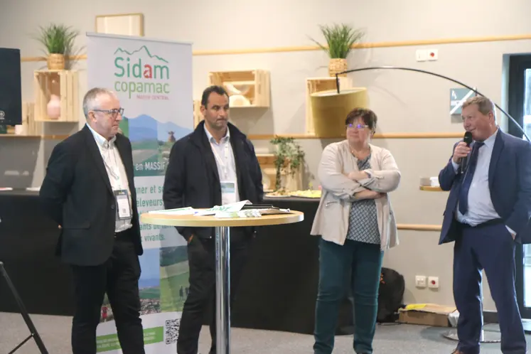 Quatre personne debout devant un kakémono sidam-copamac, l'un d'entre eux parle dans un micro
