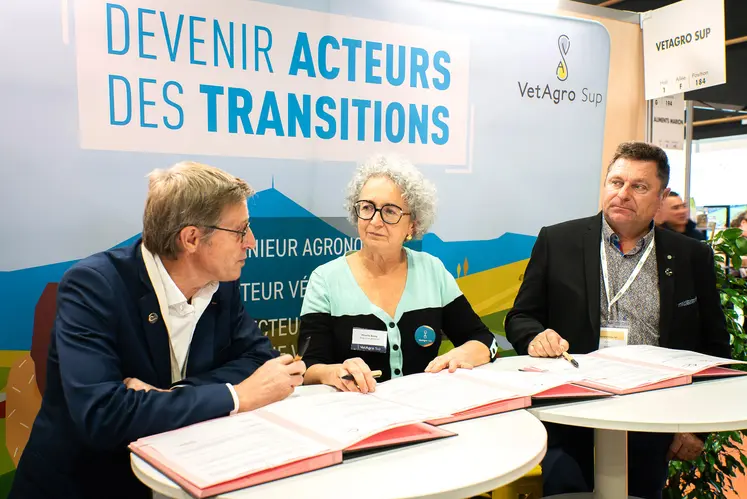 Deux hommes et une femmes assis à des table, des documents à signer devant eux