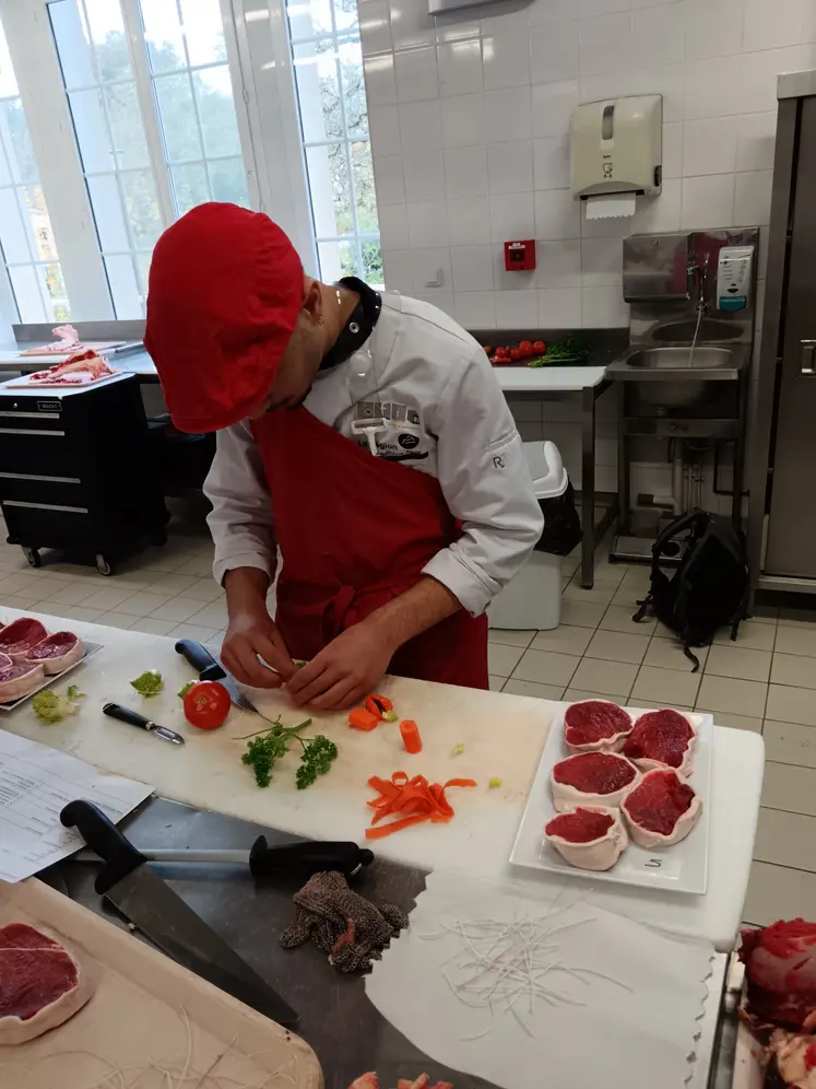 Un jeune boucher prépare des pavés de bœuf. 