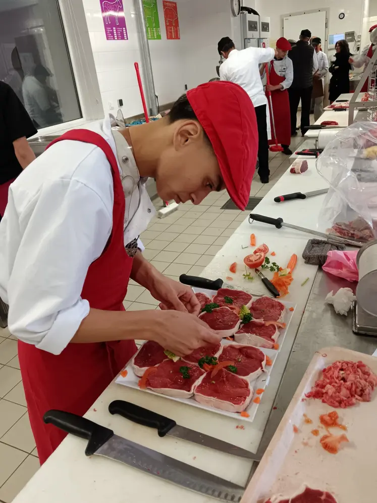 Un jeune boucher prépare des pavés de bœuf. 
