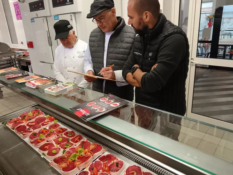 3 hommes observent et jugent des pavés de bœuf découpés par des apprentis bouchers.