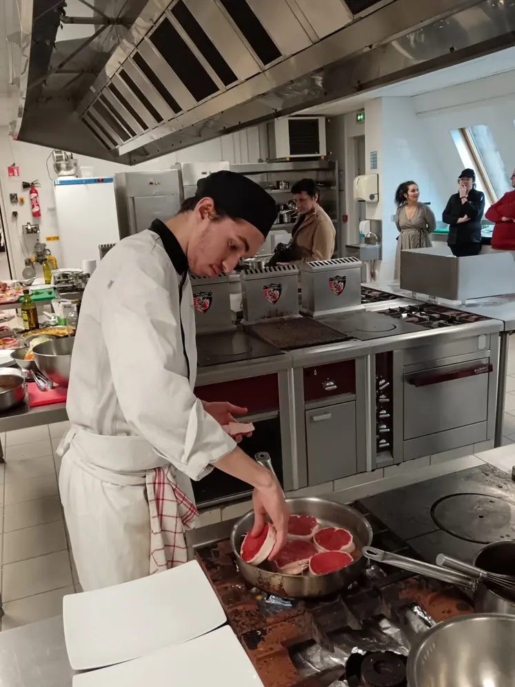 Une jeune cuisinier cuit des pavés de bœuf. 