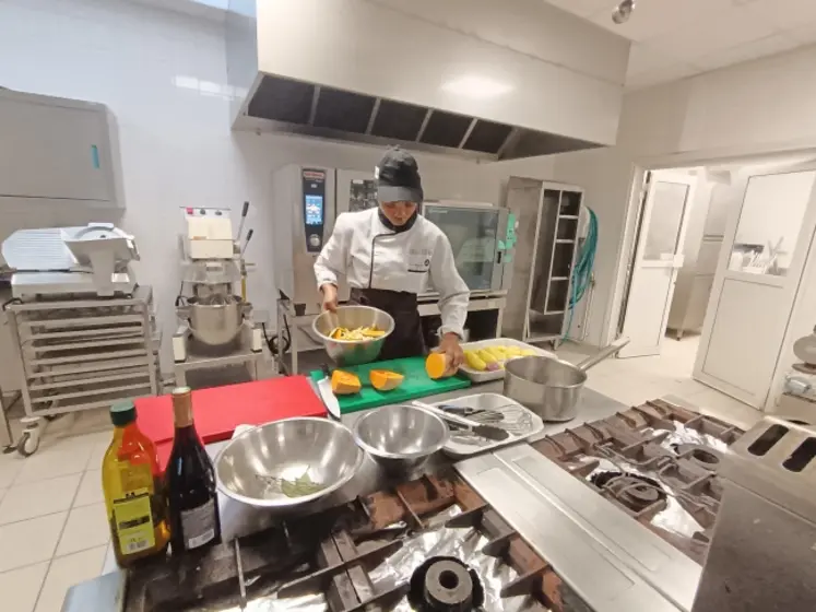 Une jeune cuisinière coupe des butternuts dans une cuisine professionnelle