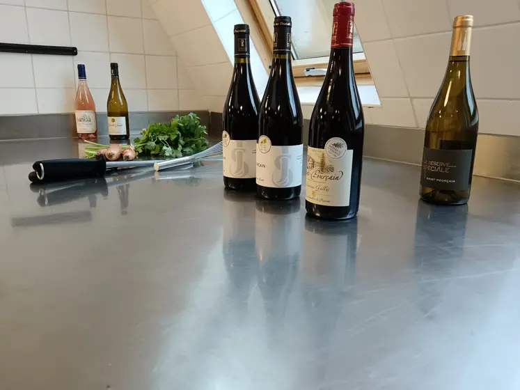 6 bouteilles de vin sont disposées sur une table en inox de cuisine professionnelle