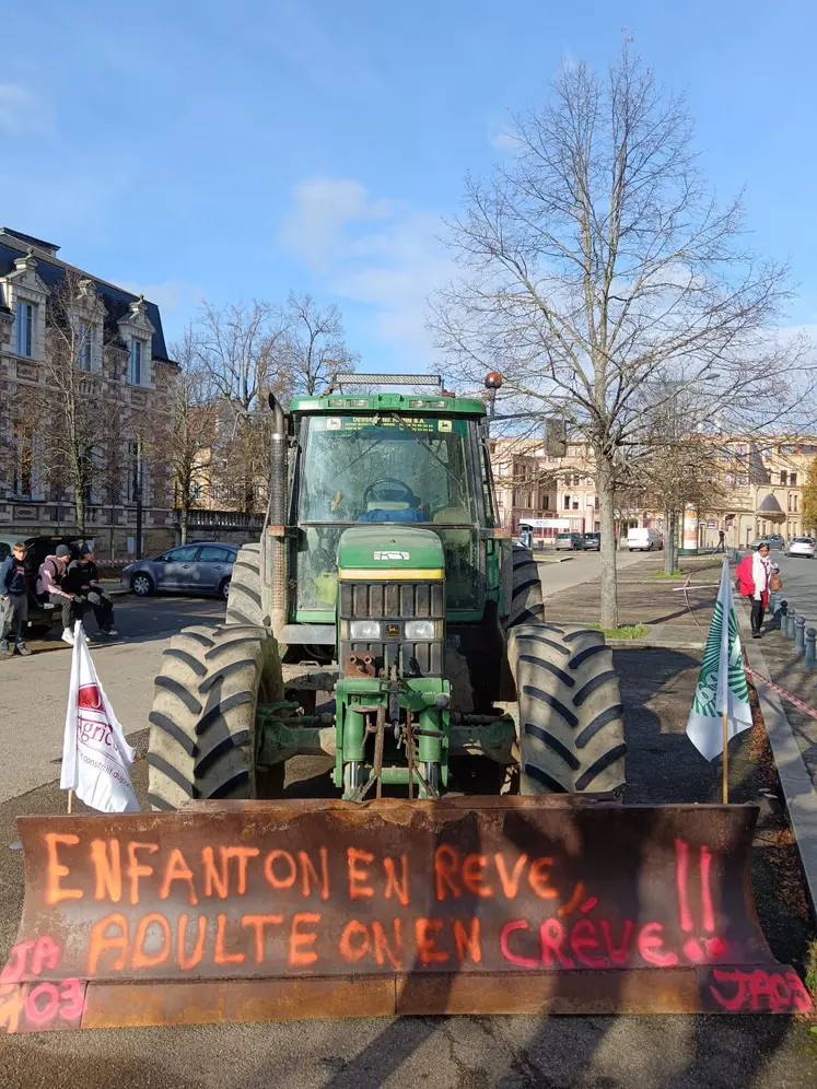 Un tracteur avec un tag "enfant on en rêve, adulte on en crève JA03" est garé devant la préfecture de l'Allier