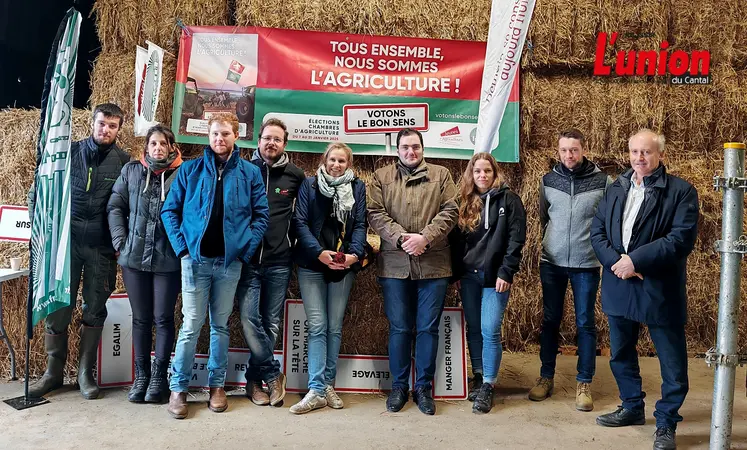 Un groupe d'agriculteurs pose devant des ballots de paille dans un grange de montagne.